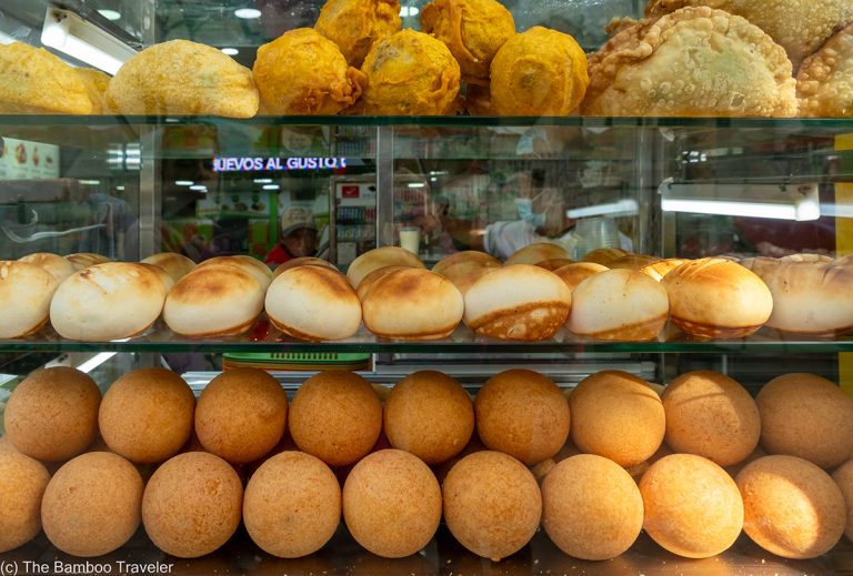a glass case filled with three rows of Colombian street food